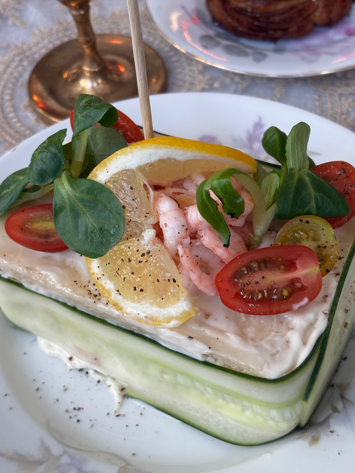 Färgfoto av en smörgåstårta dekorerad med räkor, ägg, citron och dill på ett fat.